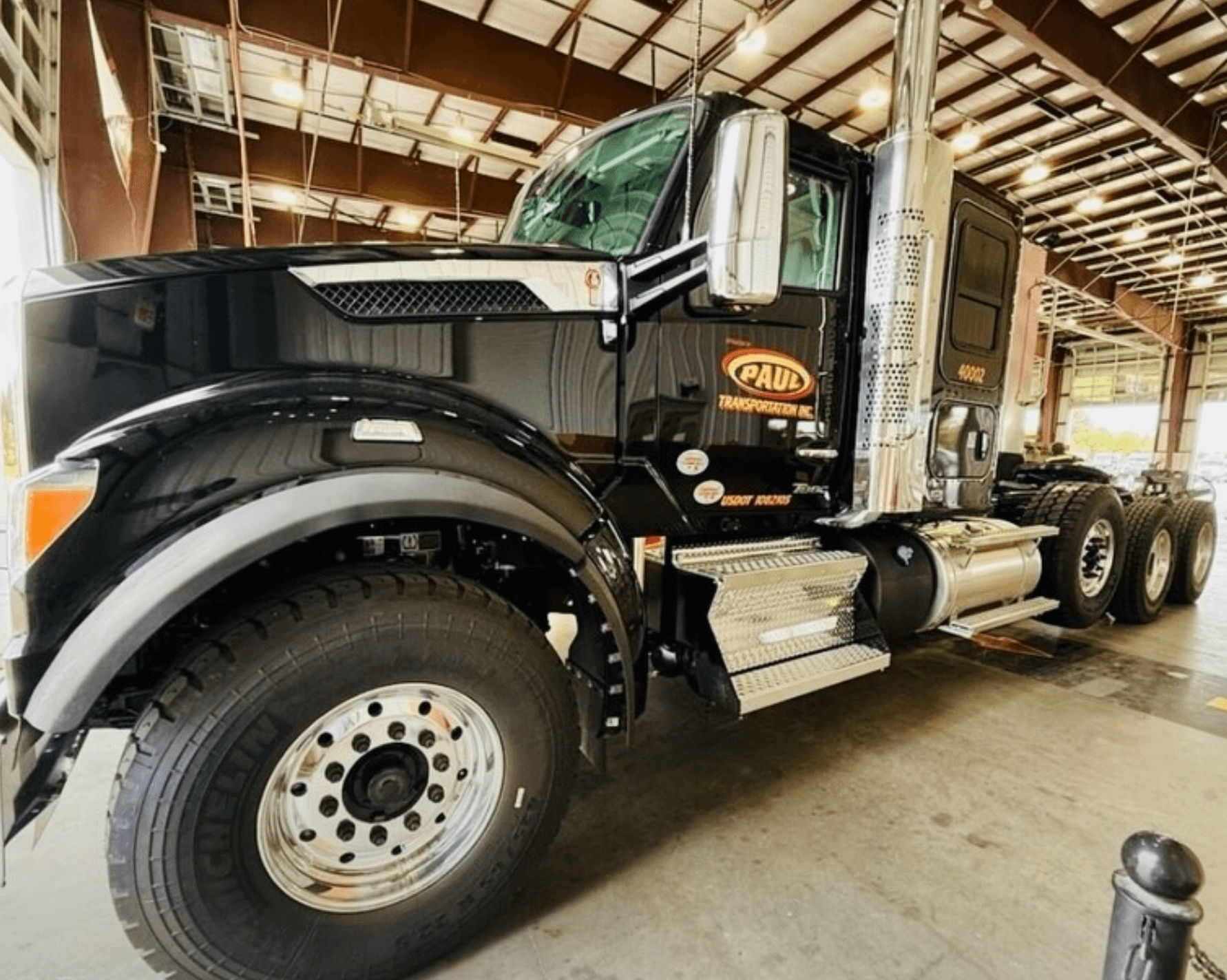 A black Paul Transportation tractor parked inside the shop.